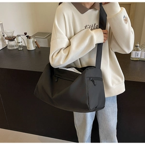 Man wearing a large black nylon travel bag with shoulder strap in a cozy cafe setting