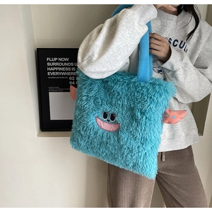 Détail du sac cabas en peluche bleue avec broderie monstre et ailes roses en relief