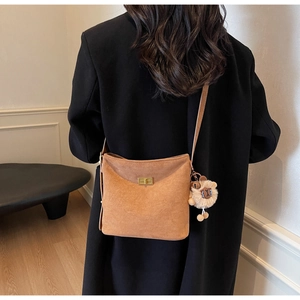Detail of brown suede bucket bag with gold metal twist lock and cute plush charm on strap