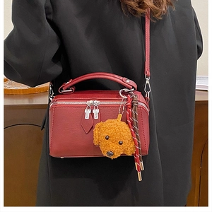 Détail du sac polochon vintage bordeaux avec charme chien en peluche et accessoires