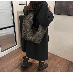 Large leopard print tote bag with black leather trim shown on a model in a minimal setting