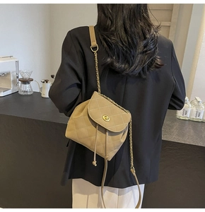 Detail van kaki gewatteerde crossbodytas met gouden draaisluiting en kettingriem bij model