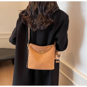 Detail view of brown suede bucket bag with gold twist lock and plush animal charm