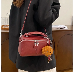 Détail du sac oreiller en similicuir rouge avec peluche chiot brun et poignée haute