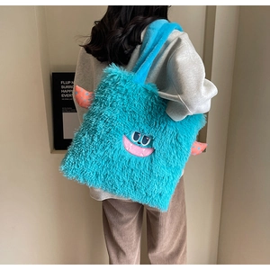 Détail du sac cabas monstre en peluche bleue avec texture douce et broderie sur modèle