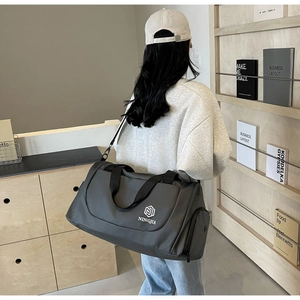 Deep grey travel bag with waterproof fabric and detachable shoulder strap on model