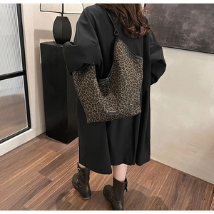 Close-up of leopard print tote bag with black leather trim and wide shoulder strap