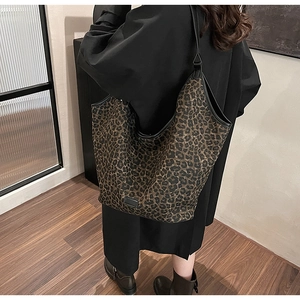 Detail of leopard print tote bag with black leather straps and reinforced trim detail