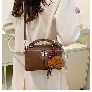 Détail d'un sac oreiller vintage marron avec breloque chiot en peluche et corde tressée