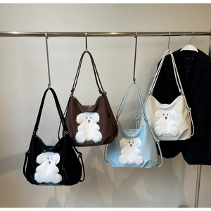 Close-up of four colored crescent tote bags with cute 3D plush animal patches on hooks