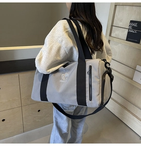 Dettaglio della borsa sportiva grigia con tracolla nera e scomparto laterale con zip