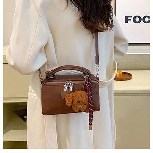 Vue détaillée du sac polochon rétro en cuir marron avec pendentif chiot peluche
