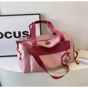 Détail du sac de sport rose et bordeaux montrant le logo NJ et la poche latérale