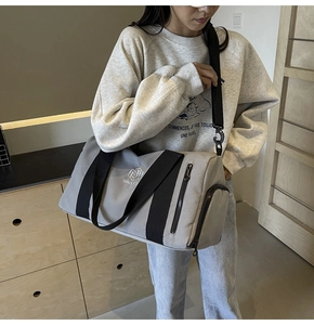 Dettaglio ravvicinato della borsa fitness grigia in tessuto impermeabile con tasche multiple