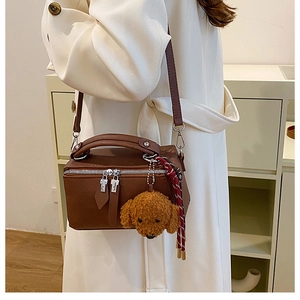 Détail du sac oreiller vintage marron avec breloque ours et ruban à rayures chic