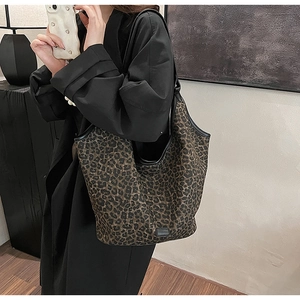 Detail showing high-capacity leopard print tote bag on model's shoulder in modern setting