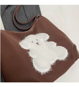 Detail of brown faux leather tote bag featuring a white plush cartoon dog patch decoration