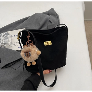 Dettaglio borsa nera in scamosciato con fibbia dorata e ciondolo lama peluche
