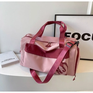 Détail d'un sac de sport rose et bordeaux avec doubles poignées et texture en nylon