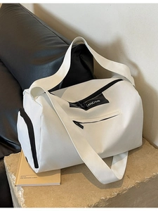 Minimalist white cylinder duffel bag with black straps and a front zipper pocket