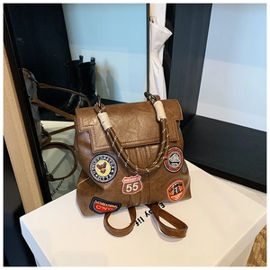 Detail of vintage brown leather backpack with retro American embroidery patches and rope handle