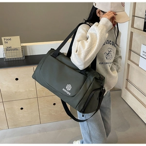 Olive green travel bag shown being carried by a model in a cozy indoor setting