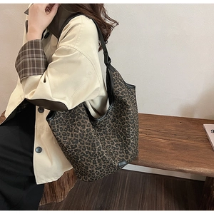 Close-up of a large leopard print hobo tote bag styled with a khaki trench coat