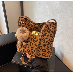 Close-up of leopard print bucket bag featuring a gold metal clasp and brown plush charm