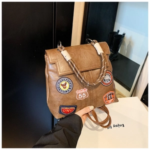 Detail of vintage brown PU leather backpack featuring colorful embroidered patches