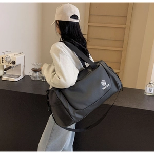 Detailed back view of a woman carrying a large black duffel bag with NINGJIA logo