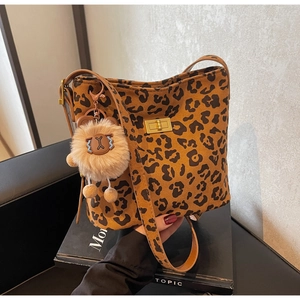 Detail of leopard print bucket bag with gold metal lock and plush lion charm