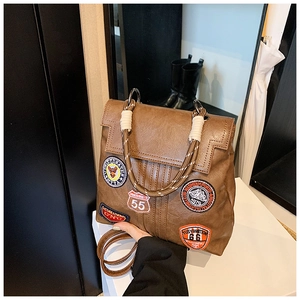 Macro detail of brown retro leather backpack with vintage embroidery patches and rope handle