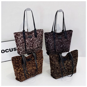 Macro detail of leopard print tote bags in grey and brown with black leather handles