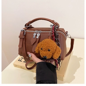 Détail d'un sac oreiller marron avec charme en peluche chien et double zip argenté