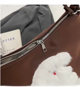Close-up of smooth silver metal zipper and white plush embroidery on brown tote bag
