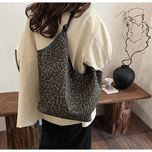 Close-up of leopard print tote bag with black leather straps on a wooden bench