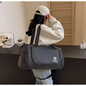 Detailed view of black nylon travel bag with shoulder strap in a cafe setting