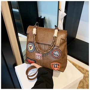 Detailed shot of vintage brown faux leather bag with colorful embroidered retro patches