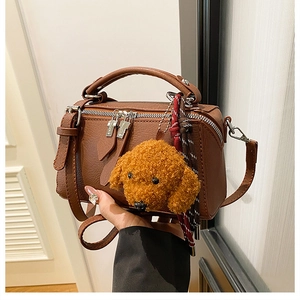 Détail d'un sac oreiller marron avec fermetures éclair argentées et charme de caniche doux