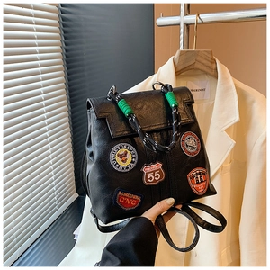 Close-up of black vintage leather backpack with retro embroidered patches and top handle