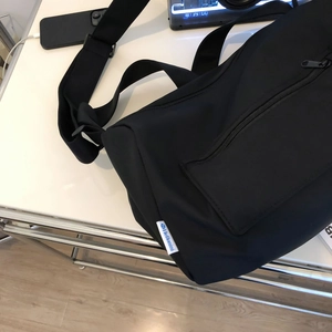Close-up of black nylon gym bag featuring wide shoulder strap and side zipper pocket