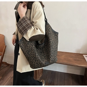 Close-up of leopard print tote bag with black leather trim worn with a trench coat