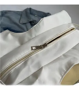 Detail of a smooth silver metal zipper on a white canvas tote bag with yellow lining