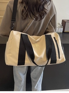 Borsa fitness in tela crema con cinturini neri portata a spalla per viaggi brevi