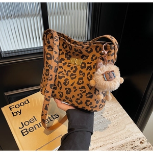 Close-up of leopard print bucket bag featuring a gold clasp and a cute plush charm