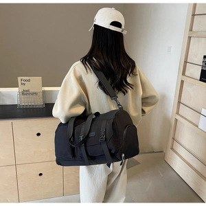Vue détaillée d'un grand sac de voyage en nylon noir avec bandoulière et poche latérale