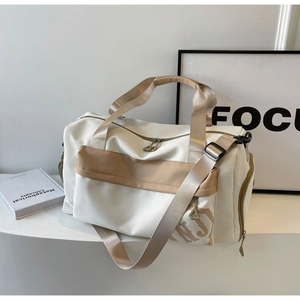 Détail du sac de voyage avec poignées renforcées et logo NJ sur surface minimaliste