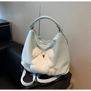 Detail of light blue tote bag featuring soft plush animal patch and smooth nylon texture