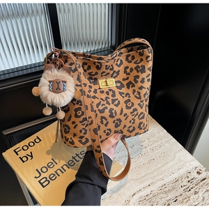 Close-up of leopard print bucket bag with gold clasp and plush bear keychain