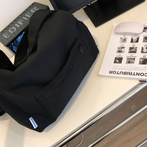 Close-up of black sports bag showing hidden side zipper pocket and blue brand label